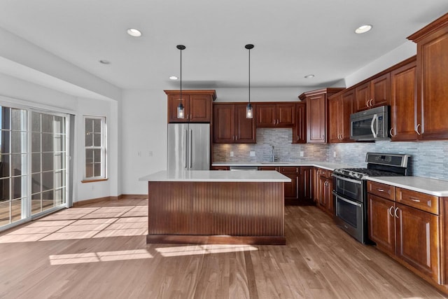 kitchen featuring appliances with stainless steel finishes, hanging light fixtures, decorative backsplash, a kitchen island, and sink