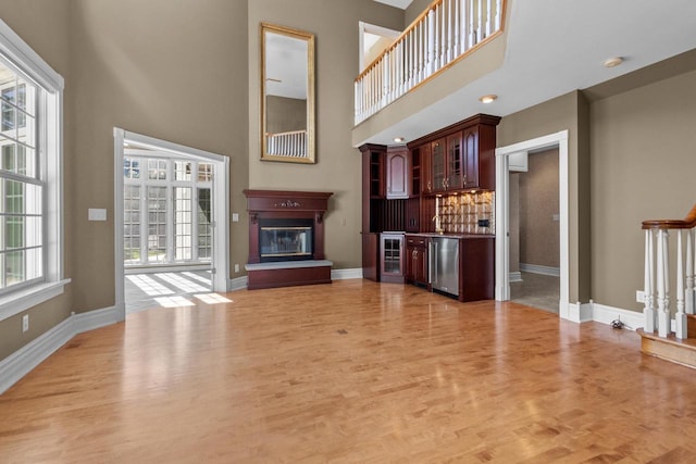 unfurnished living room featuring a high ceiling, a healthy amount of sunlight, and light wood-type flooring