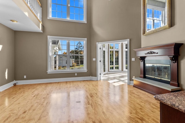 unfurnished living room with light hardwood / wood-style flooring and a towering ceiling