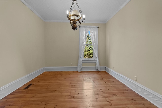 spare room with light hardwood / wood-style floors, ornamental molding, and an inviting chandelier