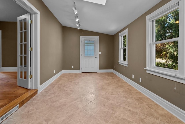 foyer with vaulted ceiling with skylight and track lighting