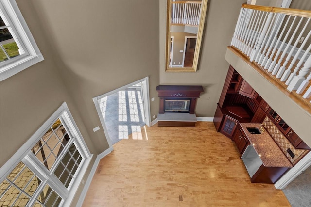 living room featuring sink, a healthy amount of sunlight, a high ceiling, and light wood-type flooring