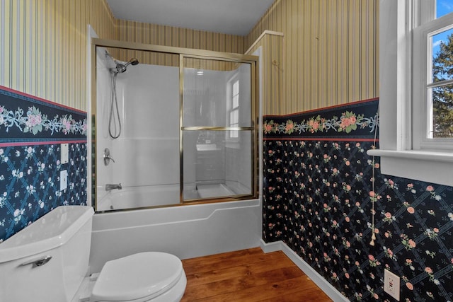 bathroom with toilet, hardwood / wood-style floors, and shower / bath combination with glass door