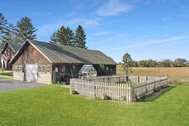 view of front of property featuring a front yard, a garage, a rural view, and an outdoor structure