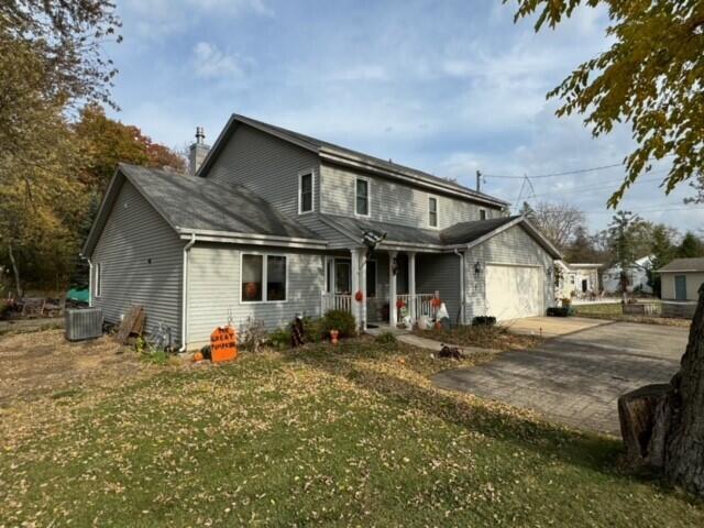 front of property with central air condition unit, a front lawn, and a garage