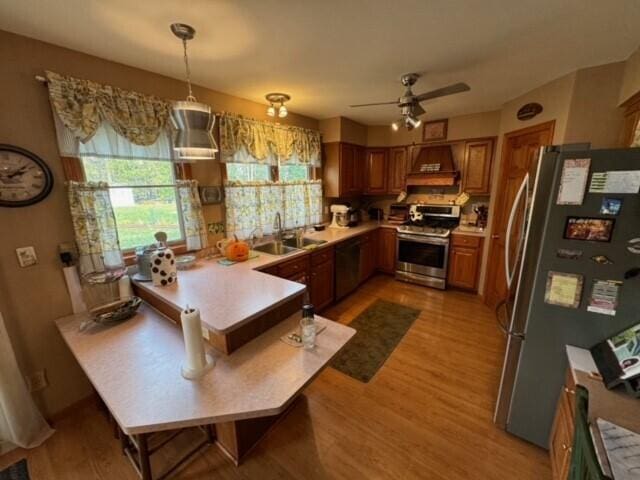 kitchen featuring stainless steel appliances, sink, pendant lighting, light wood-type flooring, and ceiling fan