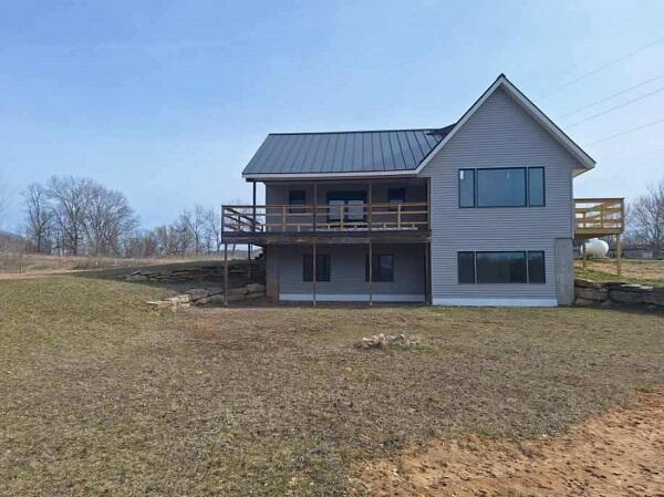 rear view of house featuring a wooden deck and a yard