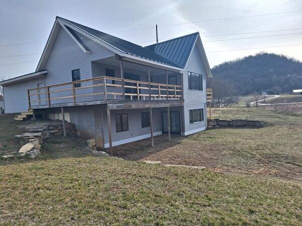 rear view of property with a lawn and a deck with mountain view