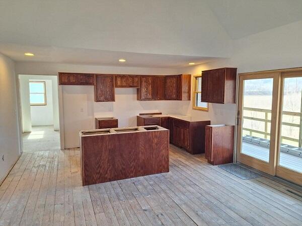 kitchen with light hardwood / wood-style floors, a center island, and vaulted ceiling