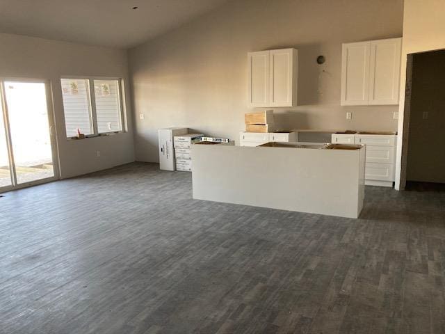 kitchen with dark wood-style floors, white cabinetry, vaulted ceiling, and a kitchen island