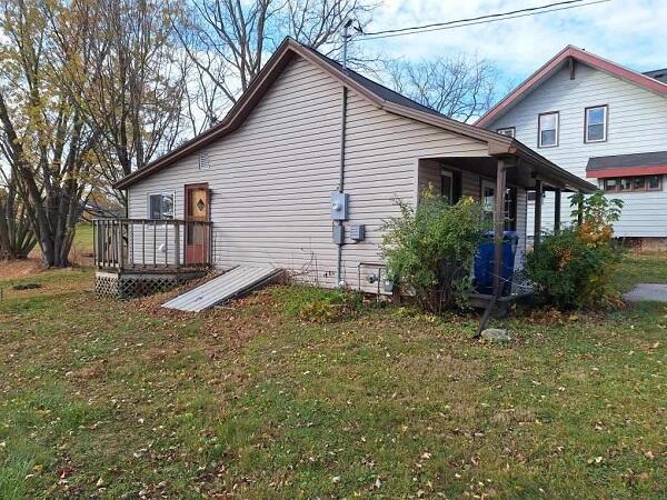 view of side of property with a wooden deck and a lawn