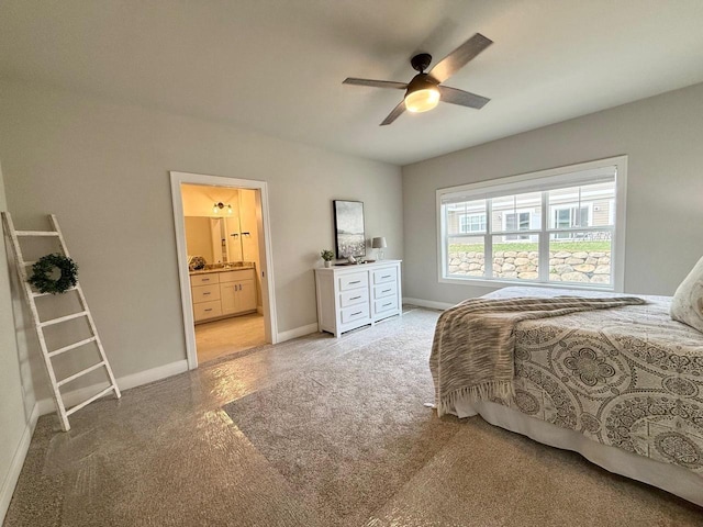 bedroom with ensuite bathroom, light colored carpet, and ceiling fan