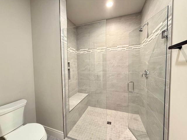 bathroom featuring a shower with shower door and toilet