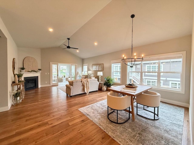 dining space with vaulted ceiling, light hardwood / wood-style flooring, ceiling fan with notable chandelier, and a healthy amount of sunlight