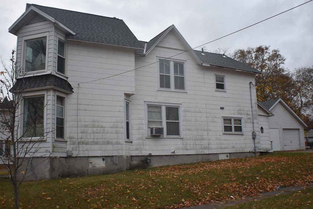 view of side of home with a lawn, cooling unit, and a garage