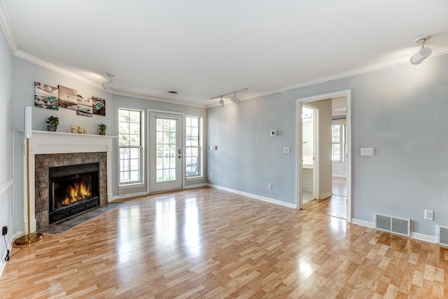 unfurnished living room with ornamental molding, a tiled fireplace, and light wood-type flooring