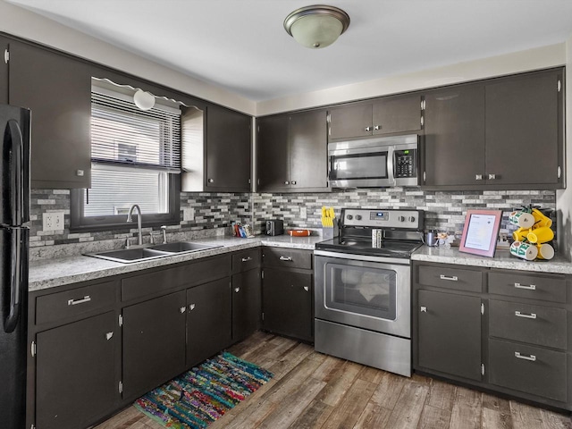 kitchen featuring sink, stainless steel appliances, light wood-type flooring, and tasteful backsplash