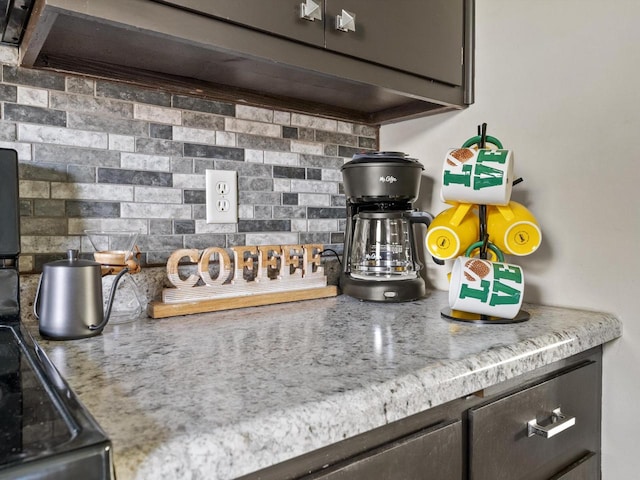 room details featuring dark brown cabinetry, tasteful backsplash, and light stone counters