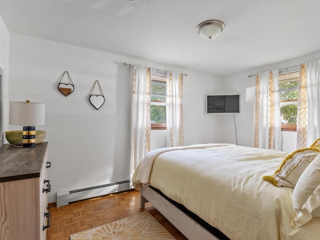 bedroom with multiple windows, a baseboard heating unit, and light parquet flooring