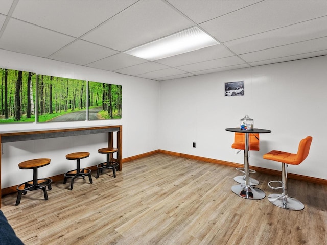 bar with light hardwood / wood-style floors and a paneled ceiling