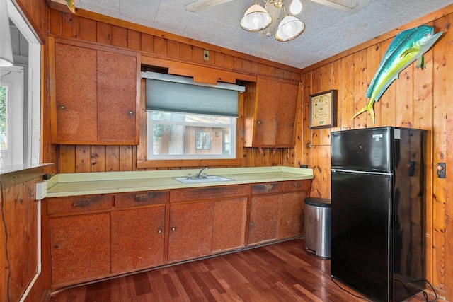 kitchen featuring wood walls, sink, ceiling fan, dark wood-type flooring, and black refrigerator