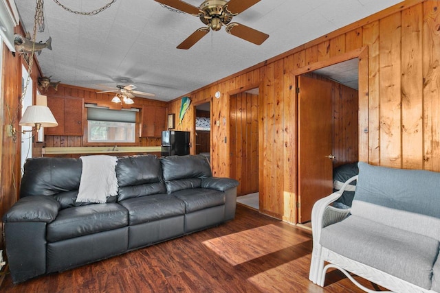 living room featuring ornamental molding, wooden walls, ceiling fan, and dark hardwood / wood-style flooring