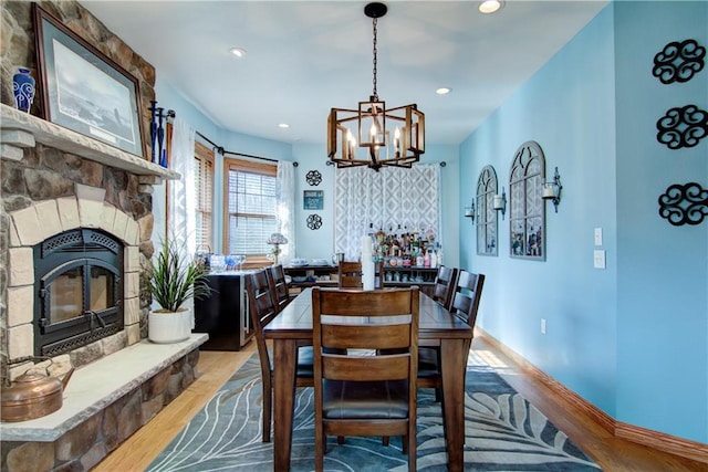 dining area with a notable chandelier, a fireplace, and light wood-type flooring