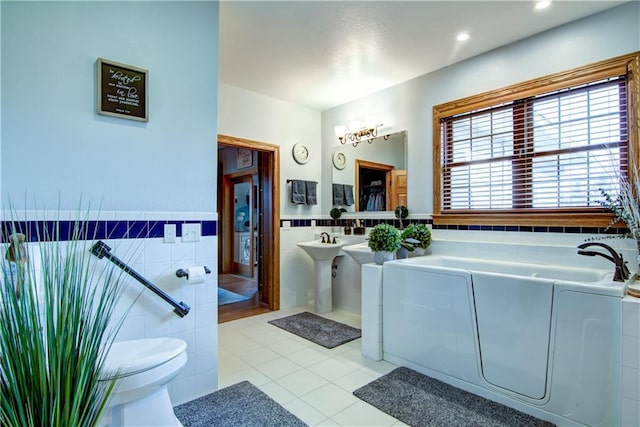 bathroom with a tub, tile patterned floors, tile walls, and toilet