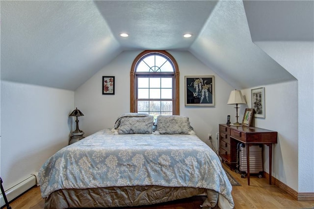 bedroom with light hardwood / wood-style floors, a baseboard heating unit, a textured ceiling, and vaulted ceiling