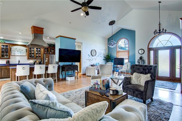 living room featuring light hardwood / wood-style floors, sink, ceiling fan with notable chandelier, and vaulted ceiling