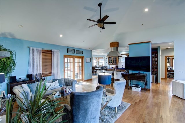 living room featuring lofted ceiling, ceiling fan with notable chandelier, and light wood-type flooring