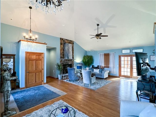 living room with lofted ceiling, a fireplace, ceiling fan with notable chandelier, and hardwood / wood-style flooring