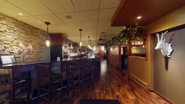 bar featuring stainless steel oven, dark hardwood / wood-style floors, hanging light fixtures, a drop ceiling, and a baseboard radiator