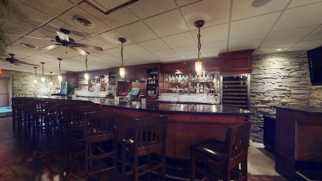 bar featuring a drop ceiling, wine cooler, hanging light fixtures, and ceiling fan