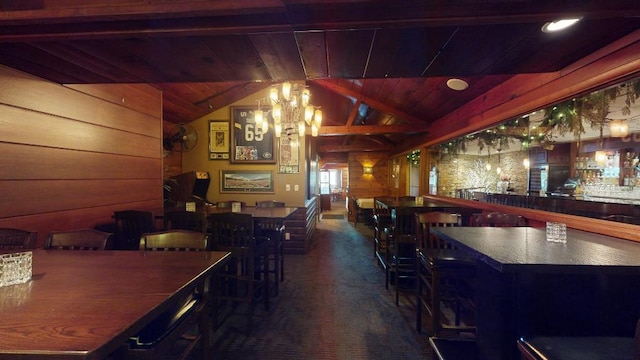 interior space with wood ceiling, a chandelier, indoor bar, wood walls, and lofted ceiling with beams