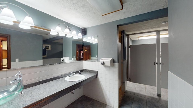 bathroom featuring tile patterned floors, a textured ceiling, sink, and tile walls