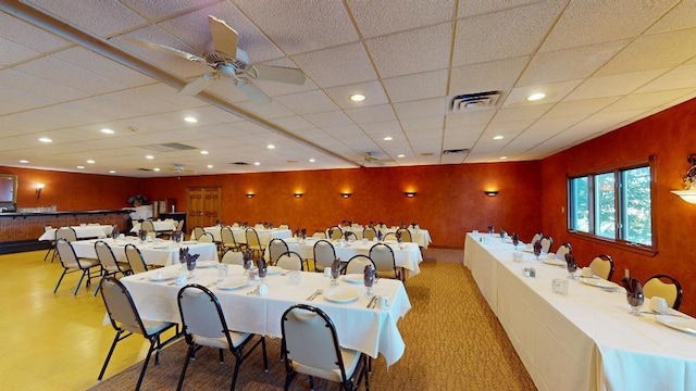 dining space with ceiling fan and a drop ceiling