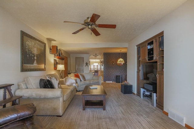 living room featuring carpet floors, a textured ceiling, a fireplace, and ceiling fan