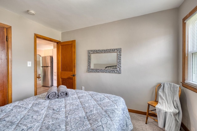 carpeted bedroom with stainless steel fridge and multiple windows