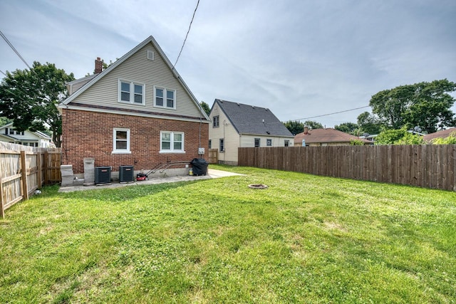 rear view of house featuring a lawn, a patio, and central AC unit