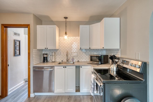 kitchen with white cabinetry, sink, appliances with stainless steel finishes, backsplash, and light wood-type flooring