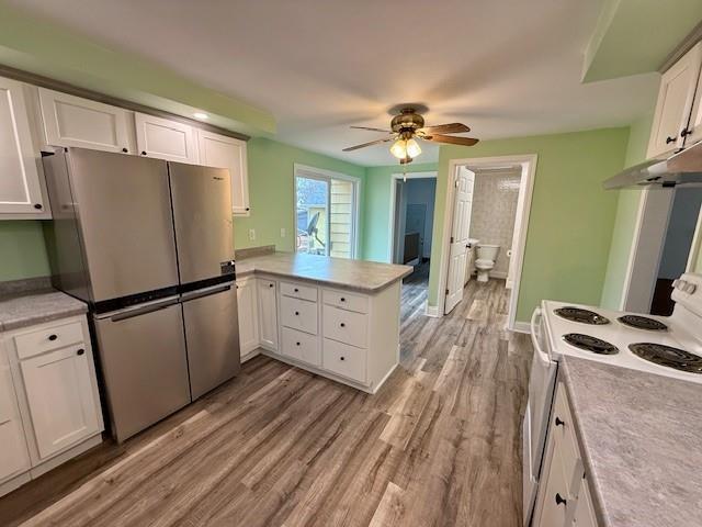 414 8th St, Baraboo, WI 53913 - kitchen featuring freestanding refrigerator, a peninsula, white electric range oven, under cabinet range hood, and white cabinetry