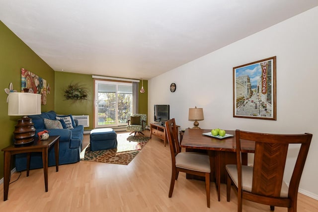 living room featuring a wall mounted air conditioner and light hardwood / wood-style flooring