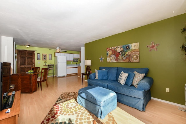 living room featuring ceiling fan and light hardwood / wood-style floors