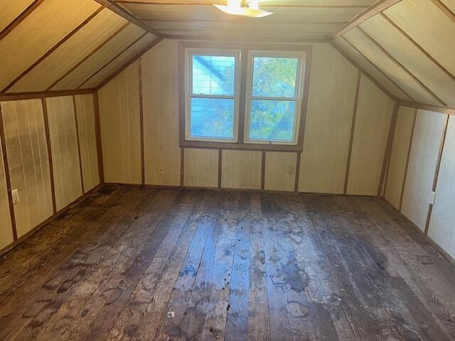 bonus room with lofted ceiling, dark hardwood / wood-style floors, and wood walls