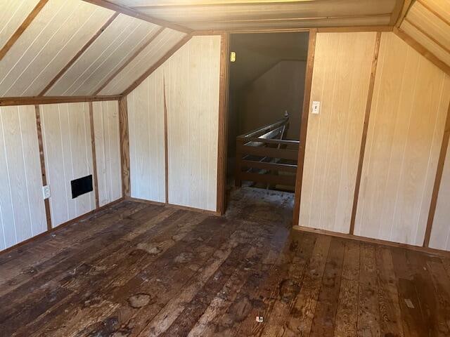 additional living space featuring lofted ceiling, dark hardwood / wood-style flooring, and wooden walls