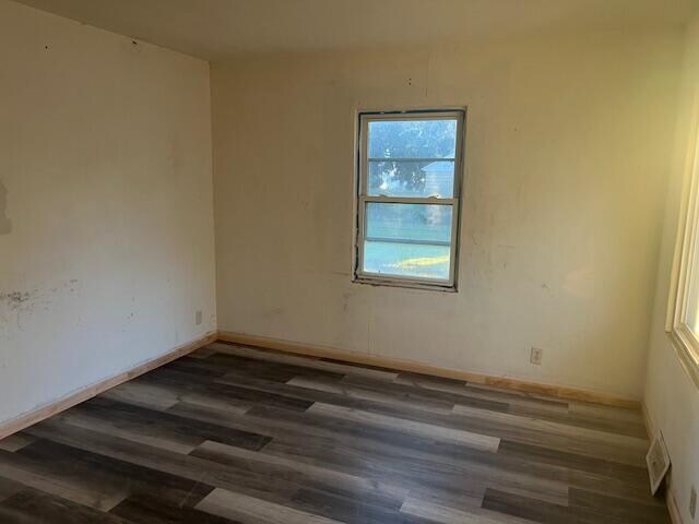 unfurnished room with dark wood-type flooring