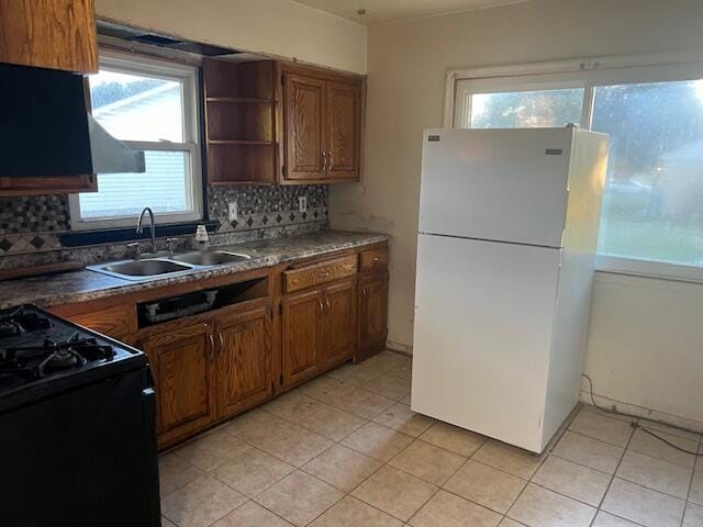 kitchen featuring black range, white fridge, sink, and a healthy amount of sunlight