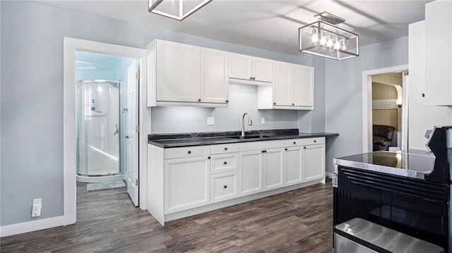 kitchen with hanging light fixtures, sink, white cabinets, and dark wood-type flooring