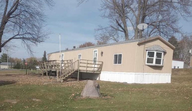 back of property featuring a deck and a lawn